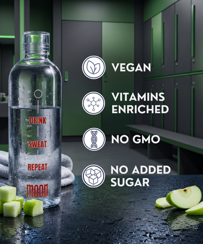 A Lunar Hydration Booster - Green Apple Flavour by MOONFREEZE FOODS PRIVATE LIMITED sits on a gym counter with apple slices, highlighting its vegan, vitamin-enriched, no GMO, no added sugar, and electrolyte-rich hydration benefits.