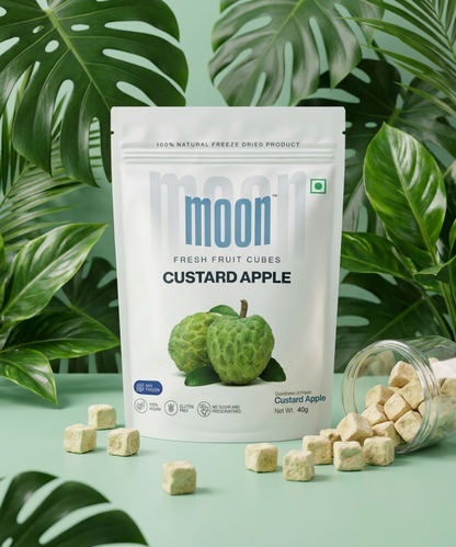 A pack of Themoonstoreindia Moon Freeze Dried Custard Apple Cubes stands upright with scattered cubes nearby, featuring no added sugar and leafy plants in the background.
