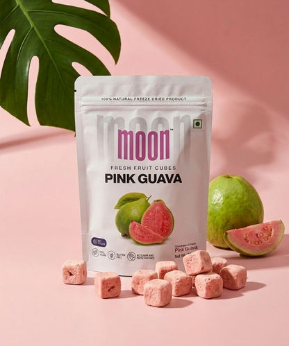 A pack of Moon Freeze Dried Pink Guava cubes by Themoonstoreindia is shown with pink guava cubes, a whole and sliced guava, and a green leaf on a pink background—rich in vitamin C and dietary fiber.