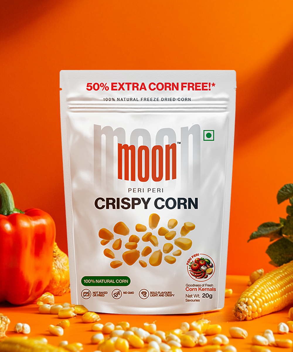 A vibrant package of MOONFREEZE FOODS PRIVATE LIMITED's Freeze Dried Crispy Corn Peri Peri rests against an orange backdrop, tempting you with a 50% extra corn offer. Decorated with images of corn and red bell pepper, it's the ultimate guilt-free treat for flavor enthusiasts.