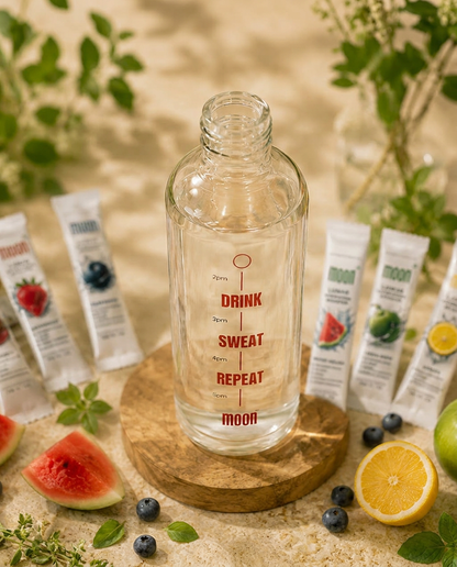 The Super Hydration Bottle (w/ Variety Pack) by MOONFREEZE FOODS PRIVATE LIMITED rests on a wooden base, surrounded by fruit, herbs, and hydration booster sachets for a refreshing twist.